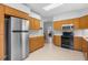 Kitchen features oak cabinets, tile flooring, and stainless steel refrigerator at 5715 Illumination Ln, Leesburg, FL 34748