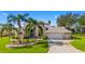 Charming home featuring a well-manicured lawn, palm trees, and a spacious three-car garage at 5740 Bounty Cir, Tavares, FL 32778