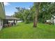 Expansive backyard with mature trees, manicured lawn, and an outdoor seating area at 8160 Se 164Th Pl, Summerfield, FL 34491