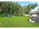 Large backyard with lush lawn, mature trees, white fence, covered patio, and ample space for activities at 8160 Se 164Th Pl, Summerfield, FL 34491