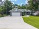 Charming single-story home with a large driveway, lush landscaping, and a well-manicured lawn at 8160 Se 164Th Pl, Summerfield, FL 34491