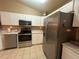 Well-lit kitchen features stainless steel appliances, white cabinets, and tile flooring at 15509 Markham Dr, Clermont, FL 34714