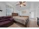 Bedroom featuring a large bed, ceiling fan, dresser and purple sofa at 1025 Capella Dr, Tavares, FL 32778