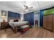 Primary bedroom featuring wood floors, large bed, ceiling fan and blue curtains at 1025 Capella Dr, Tavares, FL 32778