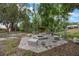 Outdoor gathering space featuring a fire pit surrounded by seating, set within a serene wooded area at 14227 County Road 455, Clermont, FL 34711