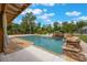 Beautiful outdoor pool area with a rock waterfall feature and lush landscaping creating a serene backyard oasis at 14227 County Road 455, Clermont, FL 34711