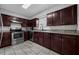 Well-lit kitchen with stainless steel appliances, granite countertops, and dark wood cabinets at 1491 Providence Blvd, Deltona, FL 32725