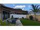 Relaxing backyard featuring a retractable awning, patio, artificial grass and nice landscaping at 1496 Lime Grove Ln, The Villages, FL 32162