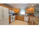 Functional kitchen featuring granite countertops, wooden cabinets, and modern appliances at 1496 Lime Grove Ln, The Villages, FL 32162