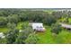 Aerial view showcases a charming home with a metal roof surrounded by lush greenery and mature trees at 15104 County Road 48, Astatula, FL 34705