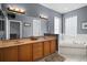 Bathroom features a double vanity, large mirror, and a separate soaking tub with decorative tile at 15104 County Road 48, Astatula, FL 34705