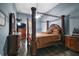 Expansive main bedroom with a four-poster bed, stylish furnishings, and dark hardwood floors at 15104 County Road 48, Astatula, FL 34705