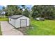 White shed with a roll-up door and side entry provides ample outdoor storage, complemented by a chicken coop at 15104 County Road 48, Astatula, FL 34705