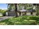 Single story home with a two car garage, lawn, and mature trees at 15925 Summit Ct, Clermont, FL 34711