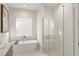 Bright bathroom featuring a modern soaking tub and a sleek glass-enclosed shower with neutral tones at 16030 Vetta Dr, Bella Collina, FL 34756