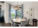 Bright dining room featuring a round table, modern chandelier, and blue patterned curtains framing a large window at 16030 Vetta Dr, Bella Collina, FL 34756