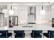 Modern kitchen with white cabinets, stainless steel appliances, quartz countertops, pendant lighting and a large island at 16030 Vetta Dr, Bella Collina, FL 34756