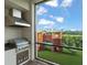 Outdoor kitchen with built in grill and view of the backyard playground on an artificial grass lawn at 16030 Vetta Dr, Bella Collina, FL 34756