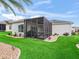 Expansive backyard featuring a screened lanai, lush green lawn, and professionally landscaped garden beds at 16863 Se 110Th Court Rd, Summerfield, FL 34491