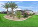 Beautifully landscaped backyard with manicured lawn, palm trees, and colorful flower beds creating a serene retreat at 16863 Se 110Th Court Rd, Summerfield, FL 34491