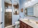 Bathroom showcasing a vanity, mirror and a walk-in shower with brown tiles and glass door at 16863 Se 110Th Court Rd, Summerfield, FL 34491