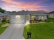 Charming home showcasing manicured landscaping and an attached two-car garage, bathed in warm sunset hues at 16863 Se 110Th Court Rd, Summerfield, FL 34491