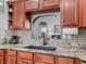 Modern kitchen features granite countertops, backsplash, and dark sink with views to living area at 16863 Se 110Th Court Rd, Summerfield, FL 34491