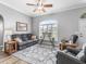 Inviting living room featuring a ceiling fan, large window with shutters, and a plush gray sofa at 16863 Se 110Th Court Rd, Summerfield, FL 34491