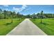 Long paved driveway leading to a beautiful home with lush greenery and palm trees at 1702 Hidden Palms Dr, Davenport, FL 33897