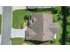 Overhead shot of the home's roof, driveway with a compass design, manicured lawn, and surrounding greenery at 2369 Unity Ter, The Villages, FL 32162