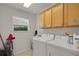 Functional laundry room with washer, dryer, storage cabinets, and a bright window at 2369 Unity Ter, The Villages, FL 32162