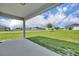 Covered porch overlooks a spacious backyard with lush green grass and clear blue skies at 2488 Begonia St, Mascotte, FL 34753