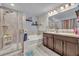 Bright bathroom featuring double vanity, soaking tub, glass shower, and modern fixtures at 2488 Begonia St, Mascotte, FL 34753