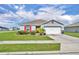 Charming single-Gathering home featuring a two-car garage, red accents, manicured lawn, and well-maintained landscaping at 2488 Begonia St, Mascotte, FL 34753