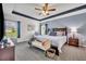 Comfortable main bedroom featuring tray ceiling, ceiling fan, and a seating area at 2488 Begonia St, Mascotte, FL 34753