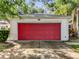 A close-up view of the home's white garage with a striking red door at 26338 Glen Eagle, Leesburg, FL 34748