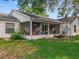 Back exterior view featuring a screened lanai, small patio, and yard with lush landscaping, creating a tranquil setting at 26338 Glen Eagle, Leesburg, FL 34748