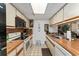 Galley kitchen with white cabinets, wood countertops, and appliances; including stove, oven, microwave, and dishwasher at 2920 Poplar Ave, Leesburg, FL 34748