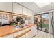 Galley kitchen with white cabinets, wood countertops, dishwasher, and stainless steel sink, plus view to back patio at 2920 Poplar Ave, Leesburg, FL 34748