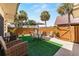 Secluded backyard patio with stylish furniture, artificial grass, tall wooden fence, and tropical palm trees at 2920 Poplar Ave, Leesburg, FL 34748