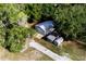 An aerial view shows a metal garage with two doors and two smaller metal outbuildings surrounded by lush trees at 3359 County Road 513, Wildwood, FL 34785