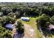 An aerial shot showcases a charming home with a detached garage surrounded by lush greenery and mature trees at 3359 County Road 513, Wildwood, FL 34785