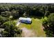 An aerial view displays the exterior of this manufactured home nestled among lush trees with ample green space at 3359 County Road 513, Wildwood, FL 34785