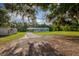 A manufactured home with a covered carport and front porch is surrounded by lush trees and sprawling green grass at 3359 County Road 513, Wildwood, FL 34785