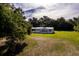 An aerial view shows a charming manufactured home on a generous green lot shaded by mature trees at 3359 County Road 513, Wildwood, FL 34785
