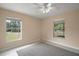 Neutral bedroom with a ceiling fan, tile floors, and a rug, with bright natural light from two windows at 37007 Forestdel Dr, Eustis, FL 32736