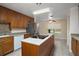 Functional kitchen featuring an island cooktop, wooden cabinets, stainless steel appliances, and tiled flooring at 37007 Forestdel Dr, Eustis, FL 32736