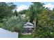 Metal outbuilding with outdoor seating area featuring lush landscaping and palm trees surrounding the space at 37138 Lake Yale Pl, Grand Island, FL 32735