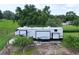 Modern recreational vehicle is parked on gravel surrounded by green grass and partial privacy fence at 37138 Lake Yale Pl, Grand Island, FL 32735