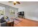 Living room featuring wood floors, a leather couch, a ceiling fan, and large windows with views of the outdoor greenery at 4445 Blue Major Dr, Windermere, FL 34786